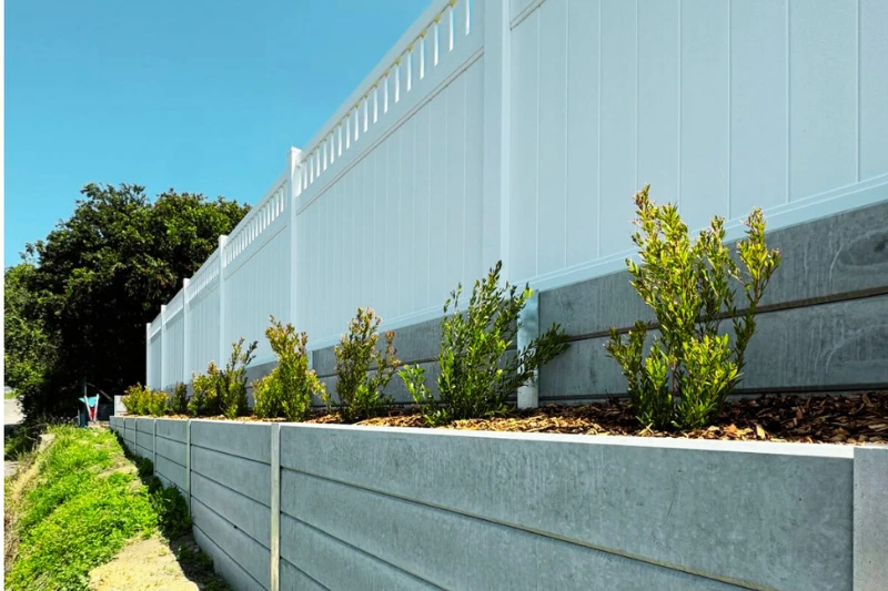 Durable white PVC fencing installed on top of a concrete retaining wall — Muller's Fencing Sydney